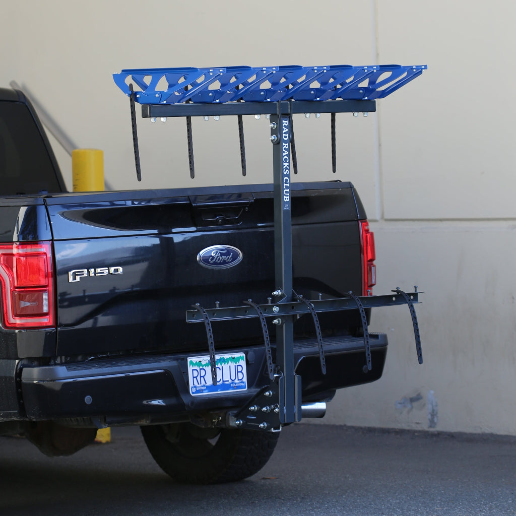 Black Ford truck with a bike rack attached to the back, parked against a gray wall.