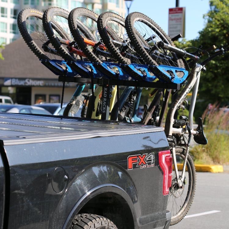 Bicycle rack attached to a car with multiple bikes on a city street. 