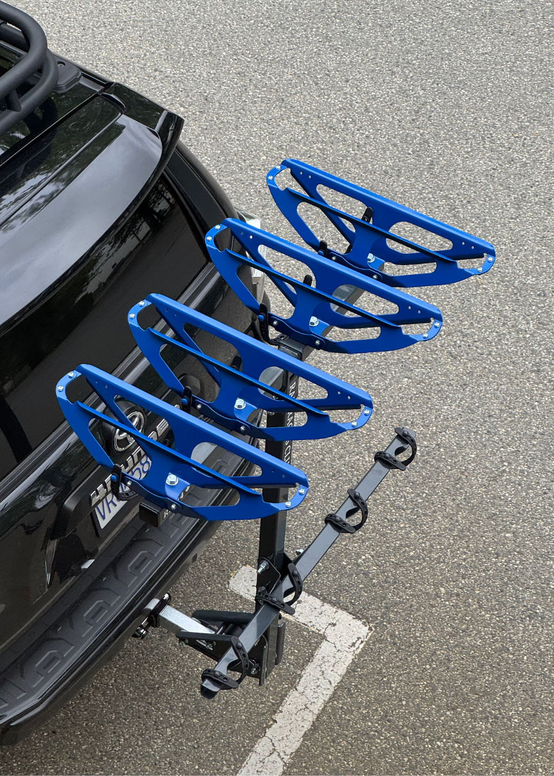 Blue bike rack on a car roof with a gray pavement background
